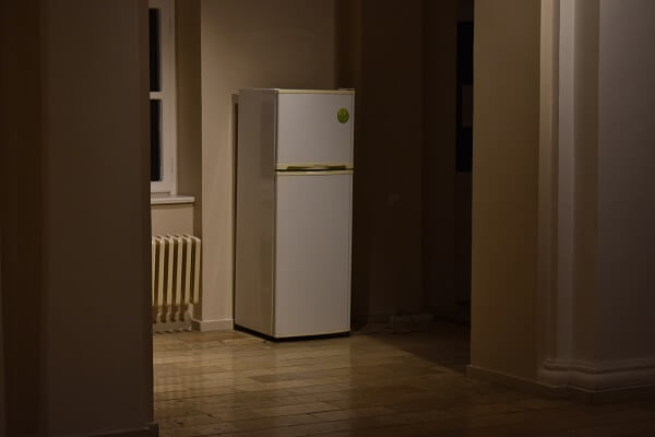 A white refrigerator in a hallway.