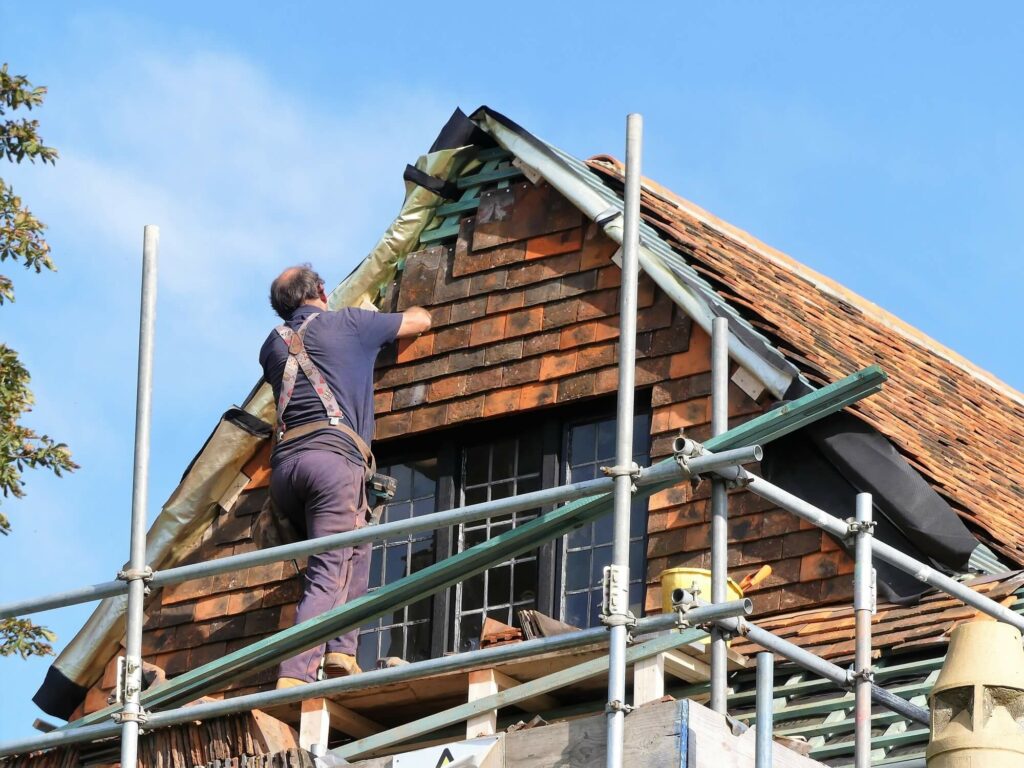 a man is repointing a roof verge on scaffold