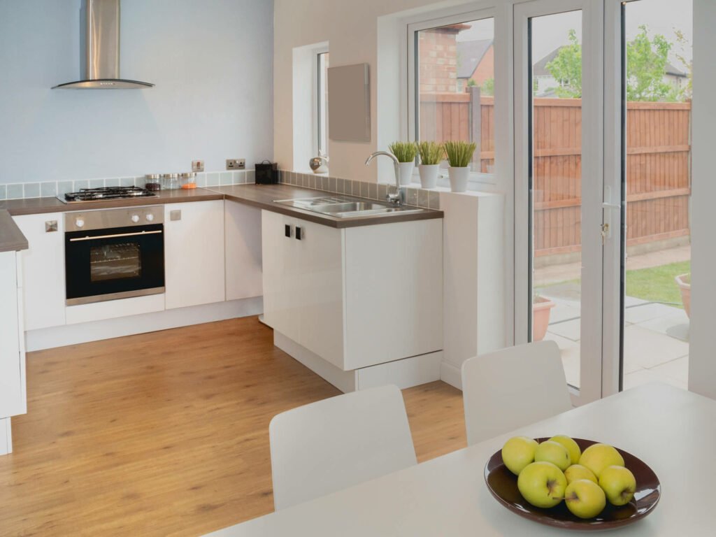 White u shape kitchen with upvc glass doors view to a patio