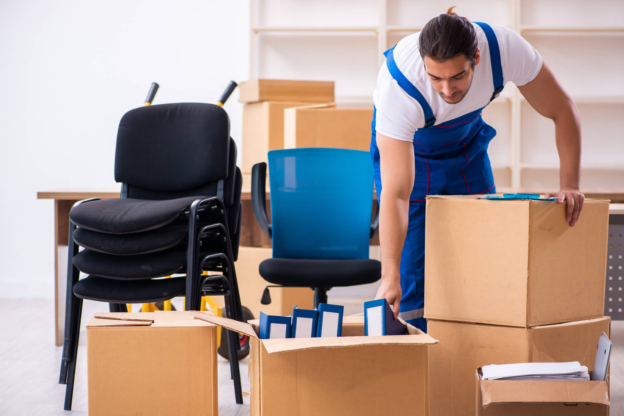 Man Packing office equipment in boxes, Stacked chairs 