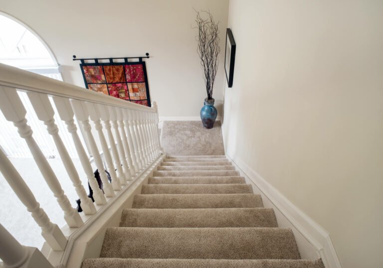 Staircase with beige carpeting