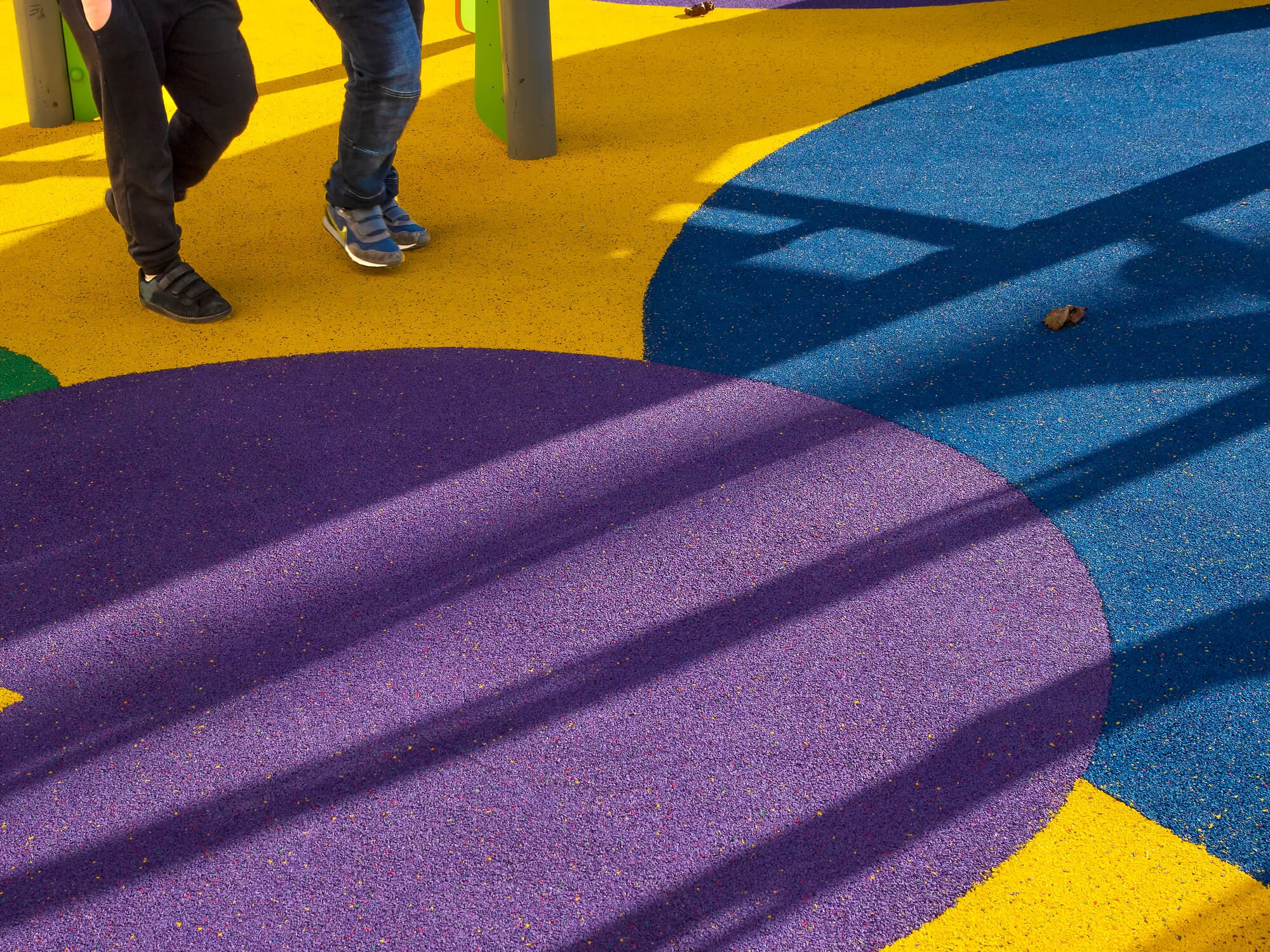 Playground surface covered with purple, blue and yellow wet pour